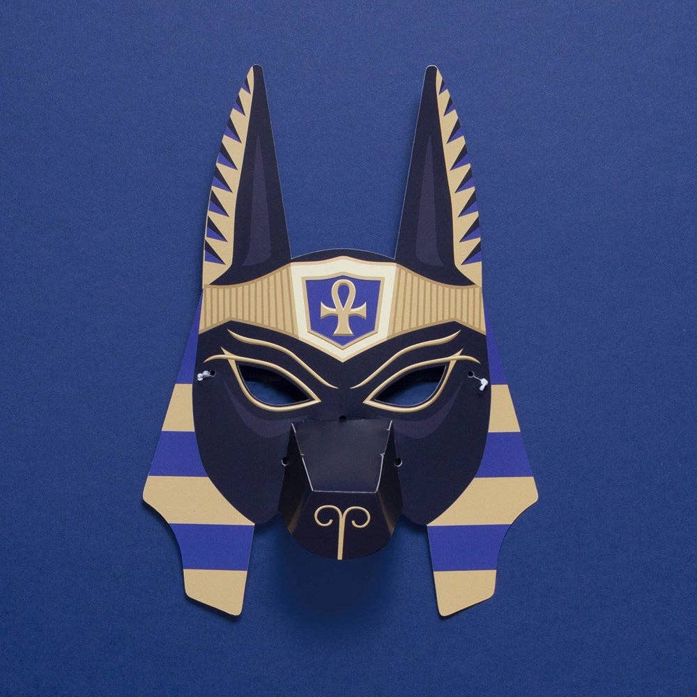 The Create Your Own Egyptian Gods Animal Masks kit features a paper Anubis mask with upright ears, gold and blue stripes, and an ankh symbol—ideal for ancient Egyptian activities or as part of Egyptian animal god masks on a blue background.