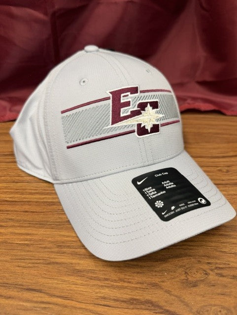 A Nike Club Lightweight Cap in light gray, featuring a maroon and white E logo with a star design on the front, is displayed on a wooden surface against a maroon cloth backdrop.