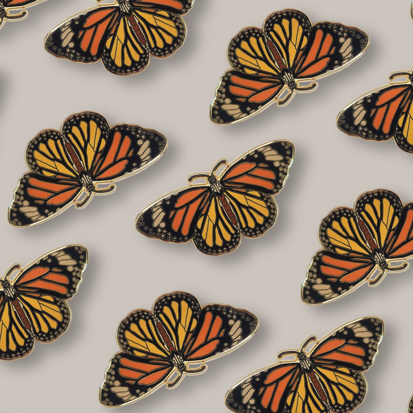 Pattern of Monarch Butterfly Educational Insect Enamel Pins featuring orange, yellow, and black wings, arranged evenly on a light gray background—perfect for butterfly jewelry lovers seeking a striking Monarch Butterfly Educational Insect Enamel Pin design.