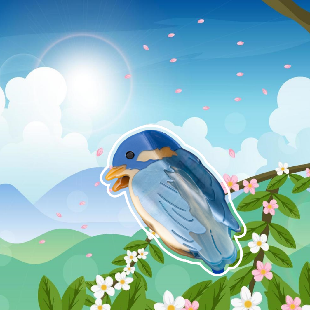 A Blue Bird Hair Claw Clip shaped like a blue jay, perched on a flowering branch.