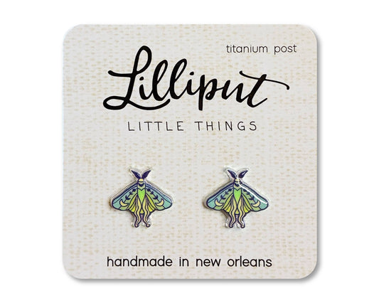Introducing the Luna Moth Earrings—a pair of moth-shaped novelty earrings featuring green and blue details, presented on a Lilliput Little Things card. These handmade, hypoallergenic earrings are crafted in New Orleans with titanium posts for sensitive ears.