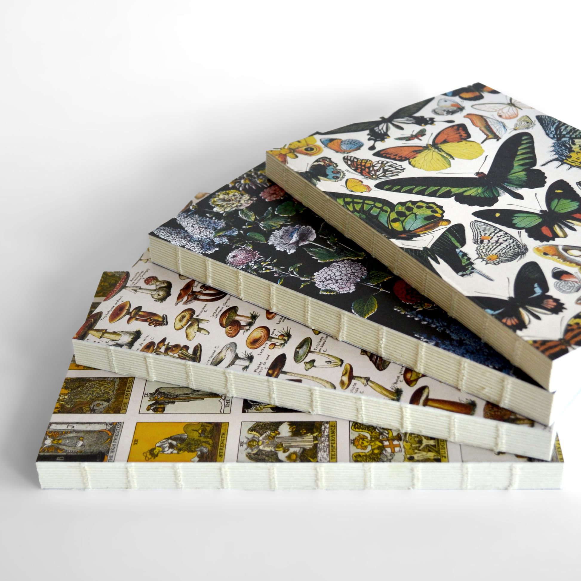 Four hardcover Vintage Botanical Flower Garden Exposed Binding Notebooks, each with a unique colorful cover—featuring butterflies, flowers, mushrooms, and vintage botanicals—are stacked diagonally on a white background.