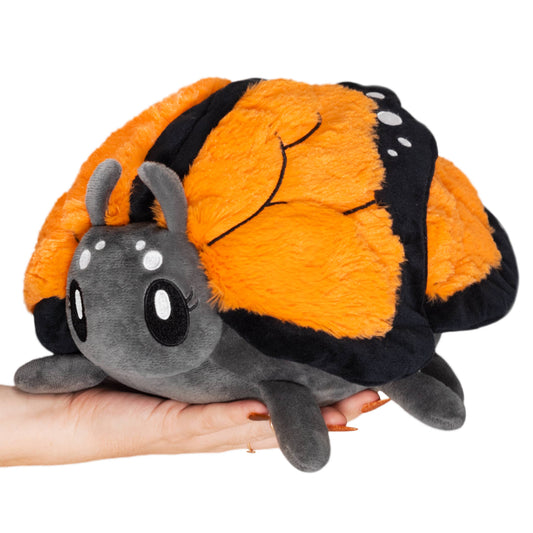 The Mini Squishable Monarch Butterfly is a plush toy with bright orange and black wings, large embroidered eyes, and white spots—perfect for butterfly fans or sensory therapy.