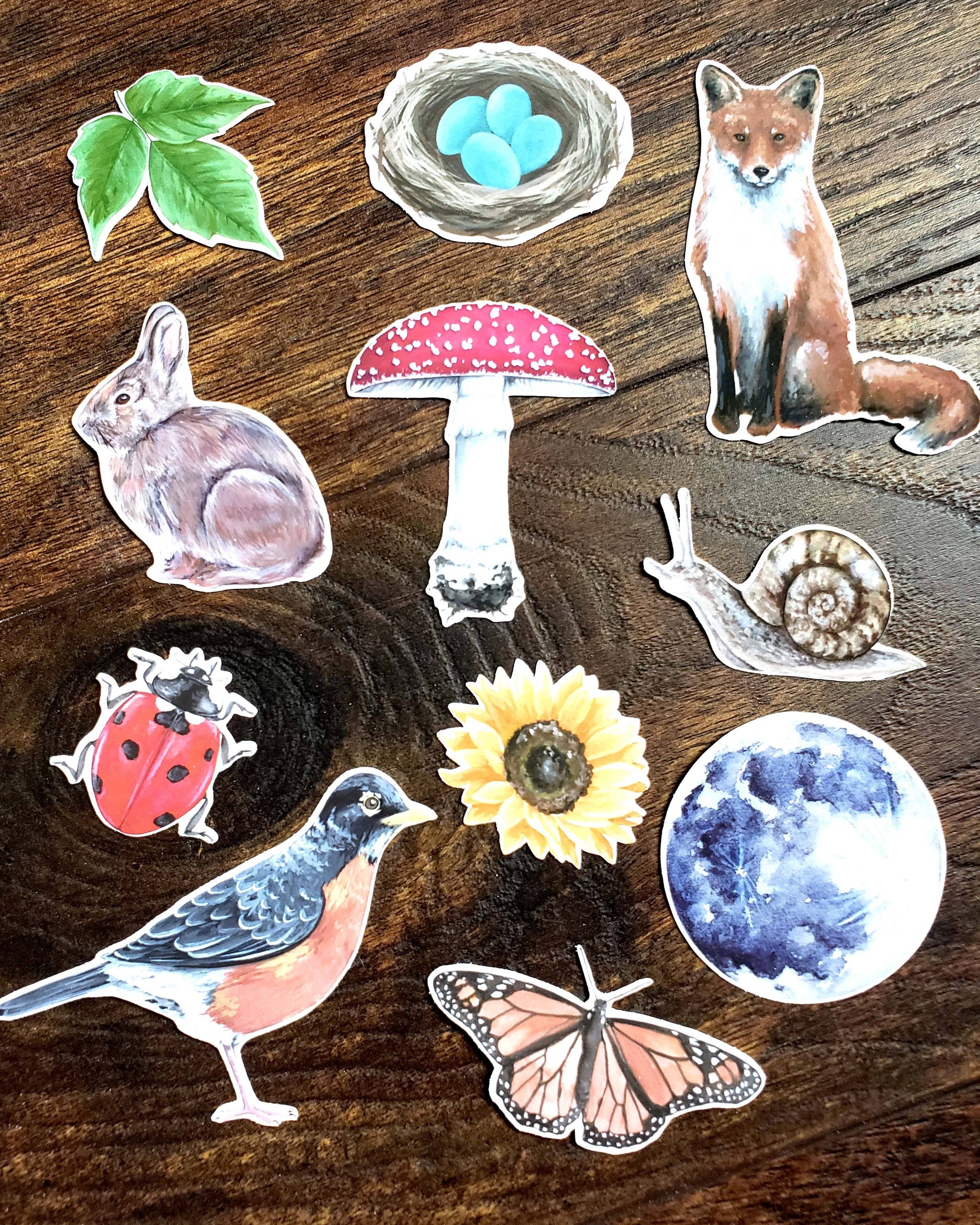 Collection of nature-themed stickers including a fox, rabbit, bird, butterfly, ladybug, sunflower, mushroom, snail, and nest.