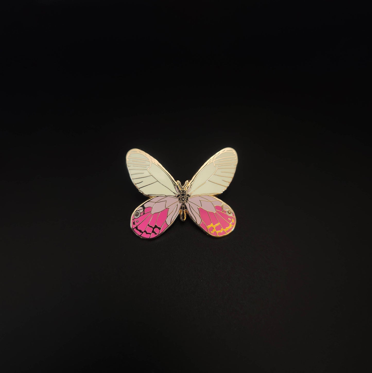 The Blushing Phantom Butterfly Educational Insect Enamel Pin showcases a rare butterfly-shaped design, featuring white upper wings and pink lower wings accented with yellow and black patterns, all beautifully presented on a plain black background.