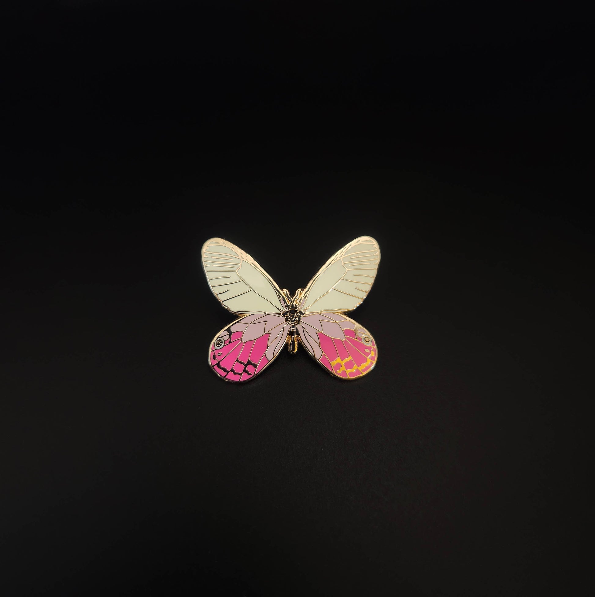 The Blushing Phantom Butterfly Educational Insect Enamel Pin showcases a rare butterfly-shaped design, featuring white upper wings and pink lower wings accented with yellow and black patterns, all beautifully presented on a plain black background.