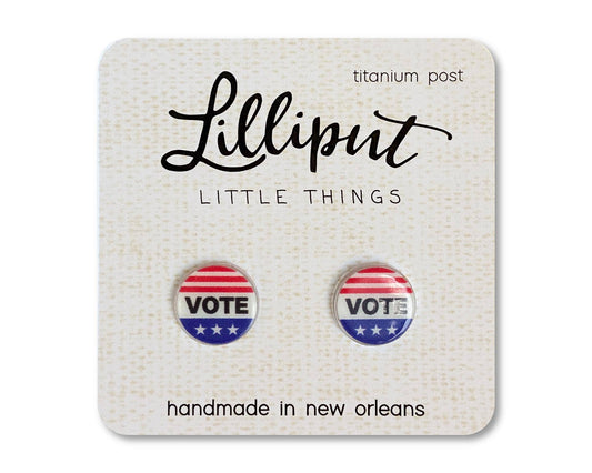 Introducing the Vote Earrings: a pair of round, hypoallergenic earrings with a red, white, and blue VOTE design. Handmade in New Orleans with titanium posts for sensitive ears, these earrings come displayed on a card labeled Lilliput Little Things.