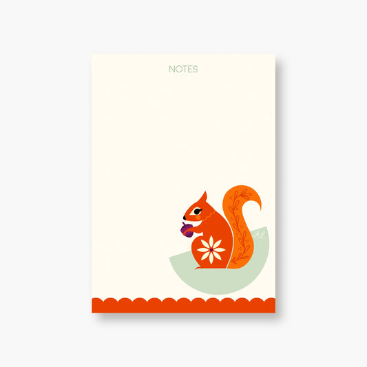 Squirrel Notepad featuring the word NOTES at the top, an illustration of an orange squirrel holding an acorn at the bottom, a scalloped red border, and a compostable sleeve.
