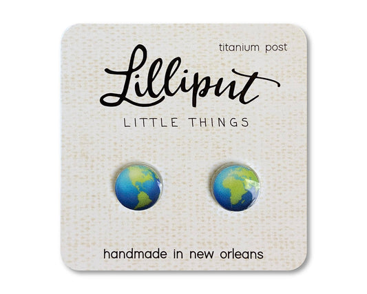 A pair of Planet Earth Earrings—round stud titanium earrings featuring an Earth design—attached to a card that reads “Lilliput Little Things,” with titanium posts, hypoallergenic and handmade in New Orleans.