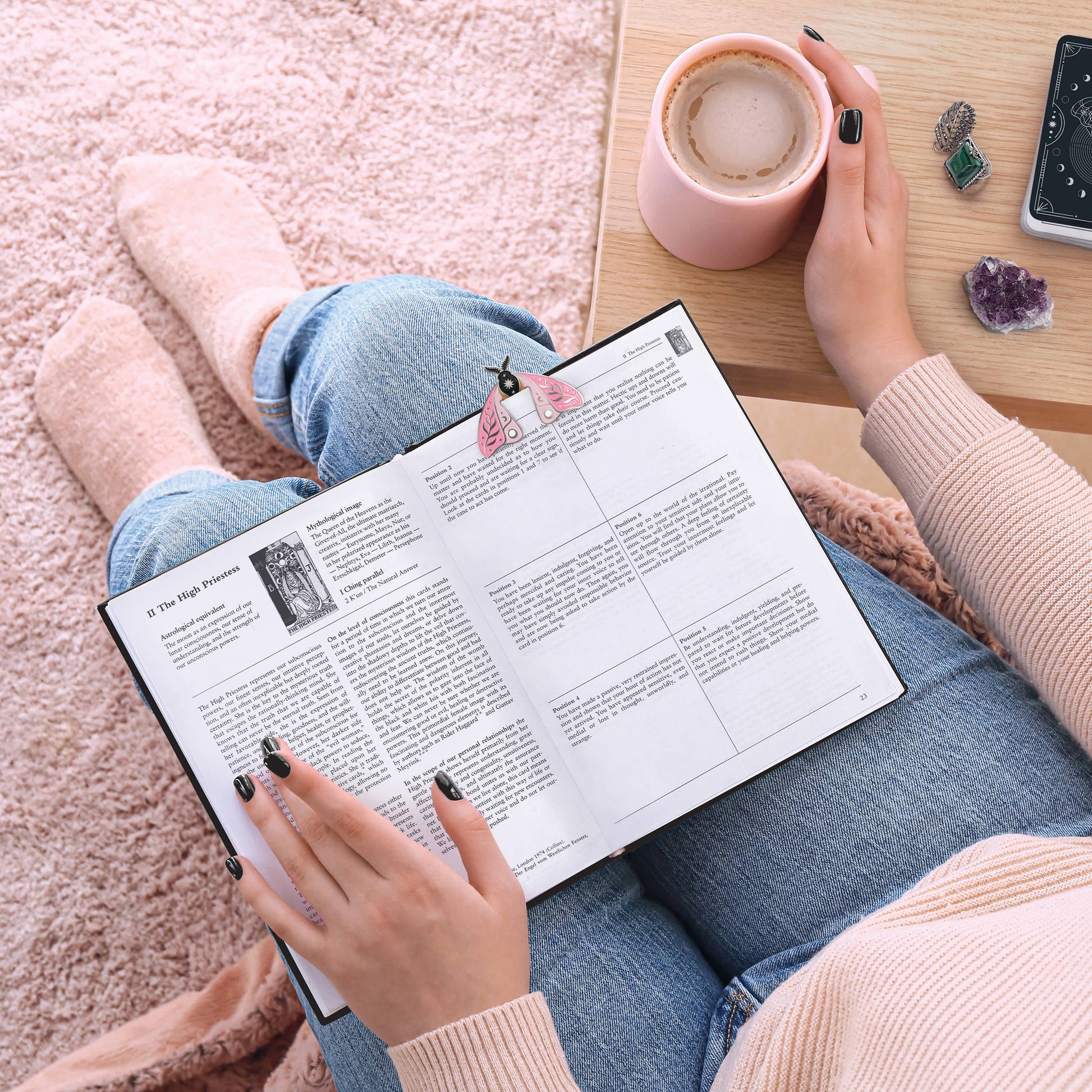 A book with a moth-shaped bookmark on top of someone's lap.