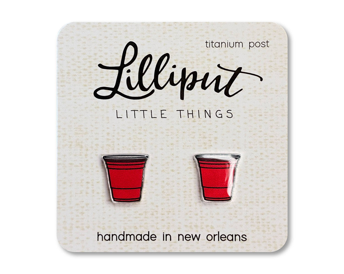 Red Party Cup Earrings—handmade in New Orleans and perfect for sensitive ears, these hypoallergenic stud earrings are shaped like small red plastic cups with titanium posts and come displayed on a card labeled “Lilliput Little Things.”.