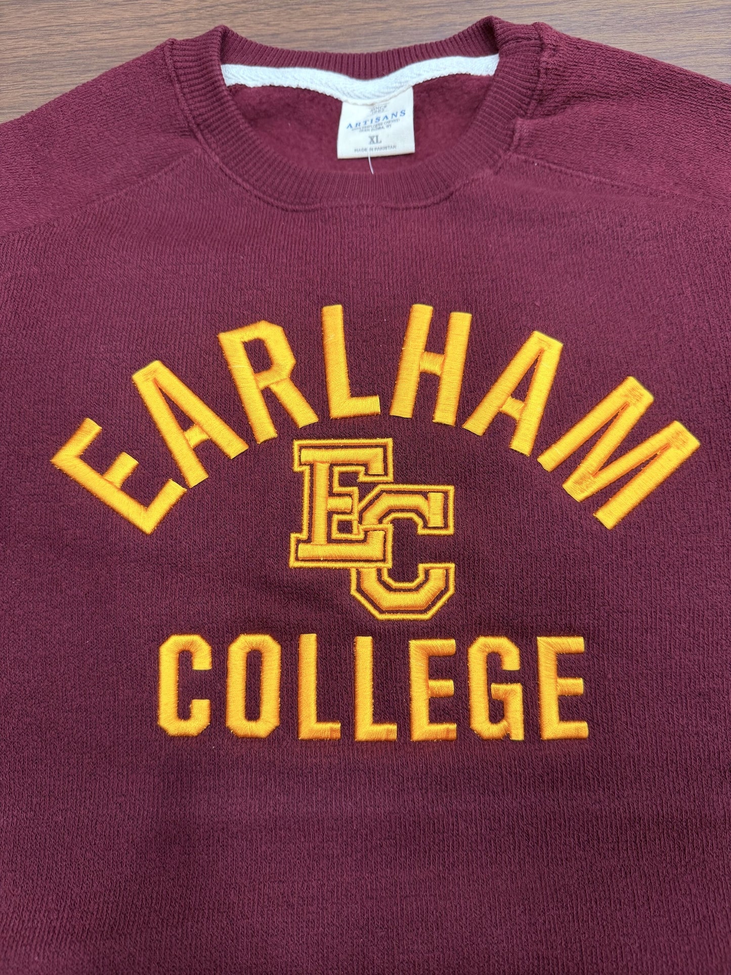 A maroon & gold embroidered sweater featuring EARLHAM COLLEGE and a yellow EC emblem on the front, tagged AMERICAN CLASSICS in size XL.