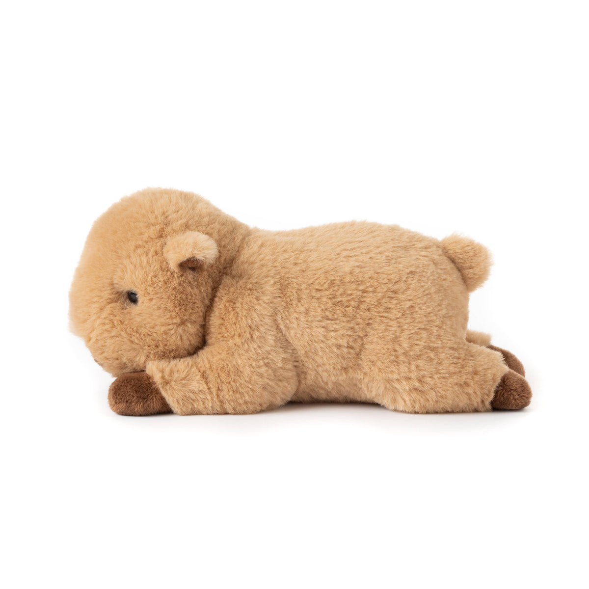 A plush, light brown stuffed Scoopz Capybara Small 8″ (21cm) lays on its stomach with its head resting on its front legs. Its fur is soft, and it has small ears and a tiny tail. Perfect as animal nursery decor, this adorable companion adds a cozy touch to any child’s space. The background is plain white.