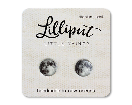Moon Earrings—handmade in New Orleans with hypoallergenic titanium posts—are a pair of round moon phase stud earrings presented on a card labeled Lilliput Little Things.