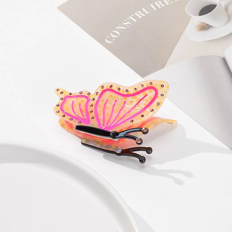 Butterfly Hair Claw Clip with translucent pink wings, orange edges, and a black base, crafted from eco-friendly acetate.