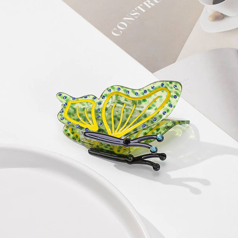 Green butterfly-shaped Butterfly Hair Claw Clip in eco-friendly acetate, embellished with small blue rhinestones.