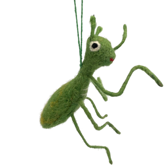 A handmade needle-felted Praying Mantis Felt Ornament with a green body, long bendable legs, and white-black eyes is suspended by a green string—ideal for display in a garden center gift shop.