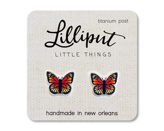 Butterfly Earrings in vibrant colors shaped like butterflies, displayed on a square white card labeled “Lilliput Little Things,” featuring titanium posts and the note “handmade in New Orleans.”.