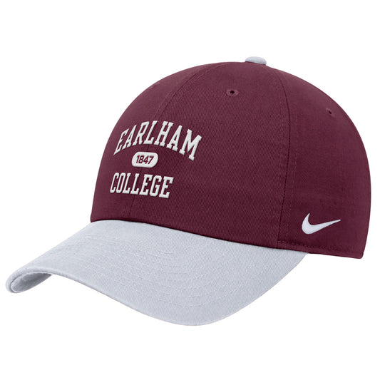 A Nike Club Colorblock Cap in maroon, featuring “Earlham College 1847” embroidered in white on the front, a white Nike swoosh on the side, and a light gray brim.