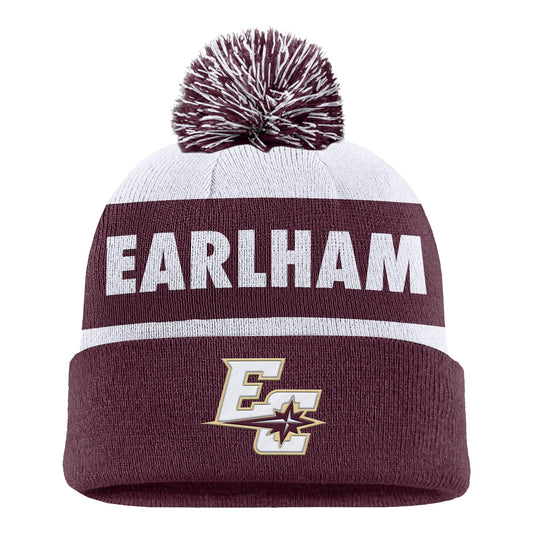 The Nike Stripe Pom Beanie is a knit hat with a pom-pom, displaying “EARLHAM” in white on a maroon and white striped background, and featuring an EC logo with a star on the maroon cuff.