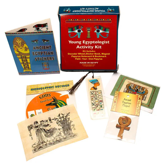 The Young Egyptologist Kit comes in a red box and includes an activity book, stickers, decoder wheel, bookmarks, papyrus notes, ankh pin, and illustrated Egyptian-themed cards.