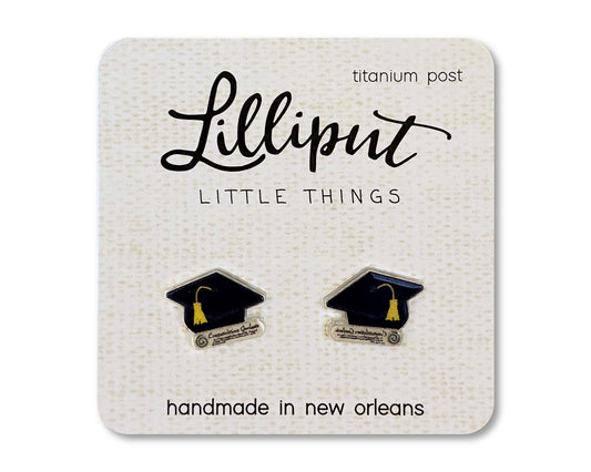 A pair of Graduation Cap Earrings featuring yellow tassels, presented on a Lilliput Little Things card, made with hypoallergenic titanium posts and handmade in New Orleans.