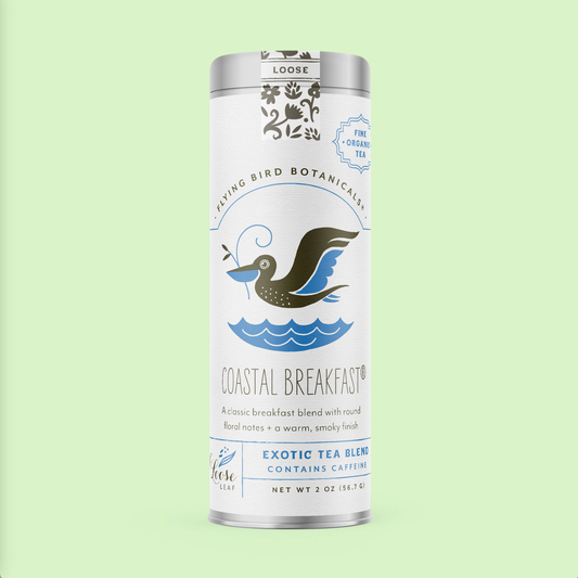 A cylindrical tin of Coastal Breakfast (ORG) – Loose Leaf Tin featuring a graphic of a bird carrying a branch over water, with floral notes printed on the label.