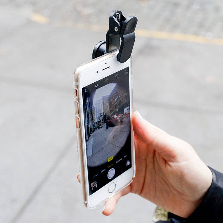 A hand holds a smartphone with the Phone Lens Kit S/3 wide-angle lens attached, capturing sharp city street views on the screen—demonstrating how the kit can enhance mobile photography.