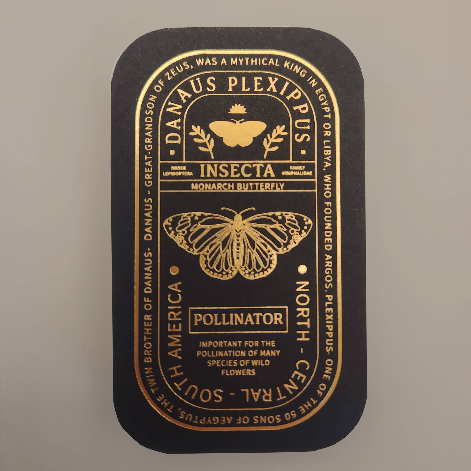 A sleek black tin adorned with gold text and illustrations, featuring a butterfly and bee. The inscriptions read “Danaus Plexippus” and “Insecta,” offering fascinating facts about monarch butterflies as pollinators. Designed for collectors and nature lovers alike, this tin is the perfect way to display your Monarch Butterfly Educational Insect Enamel Pin or other favorite butterfly-themed jewelry.