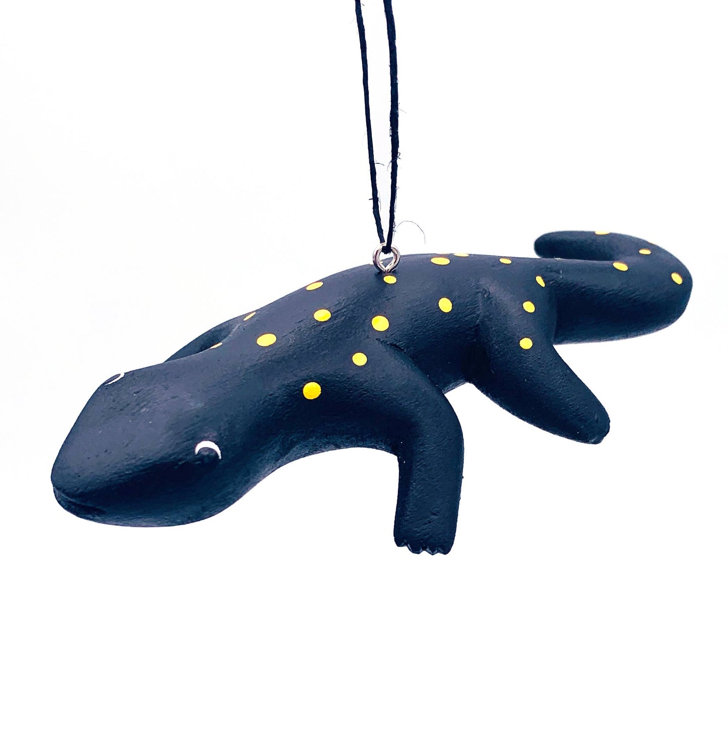 The Spotted Salamander Balsa Ornament is a handmade fair trade piece, featuring black with yellow spots and white eyes, hanging by a black string—hand-carved for unique charm and character.