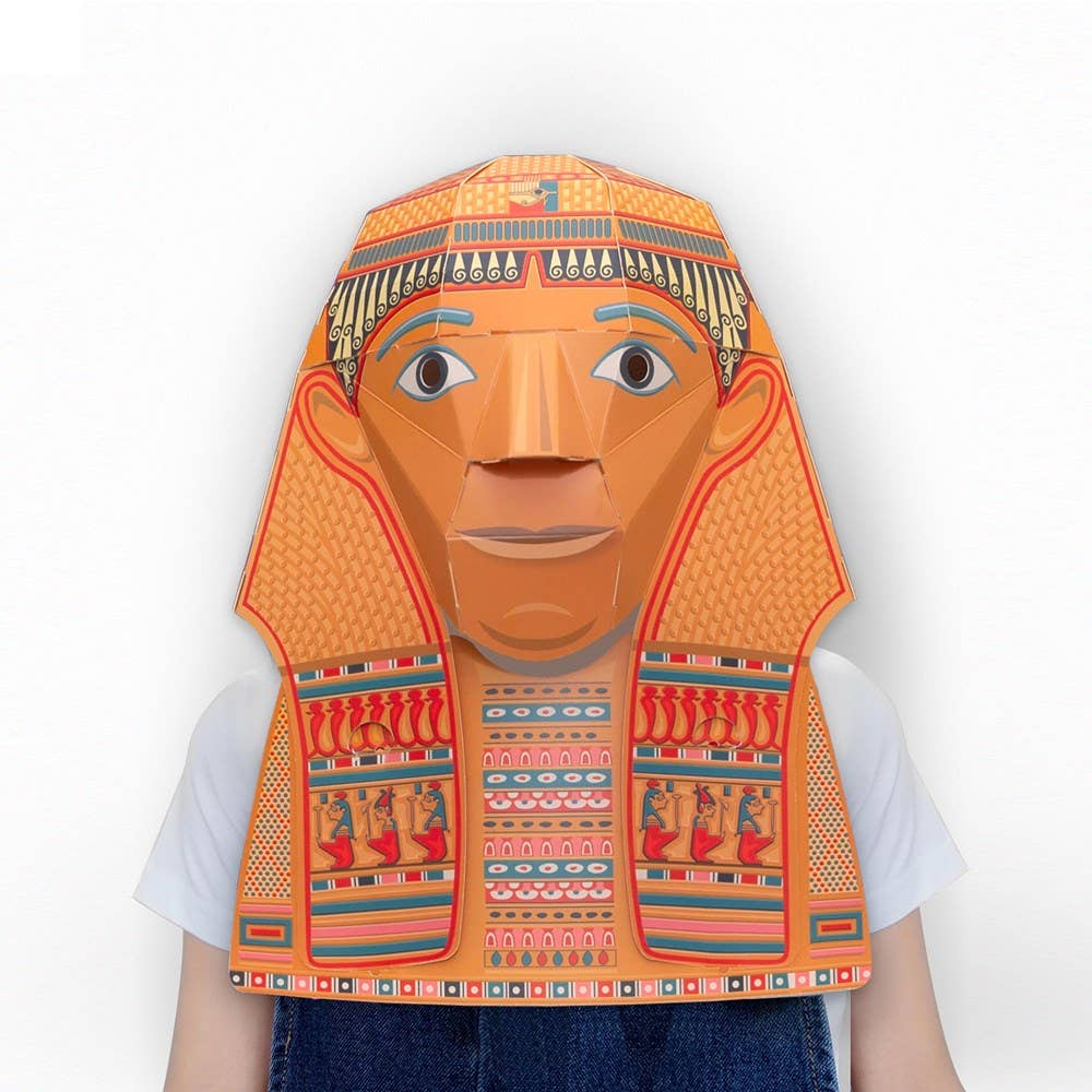 A person wears the Create Your Own Egyptian Head Mask, featuring colorful geometric patterns and a headdress, over a white shirt and denim overalls, standing against a plain white background.