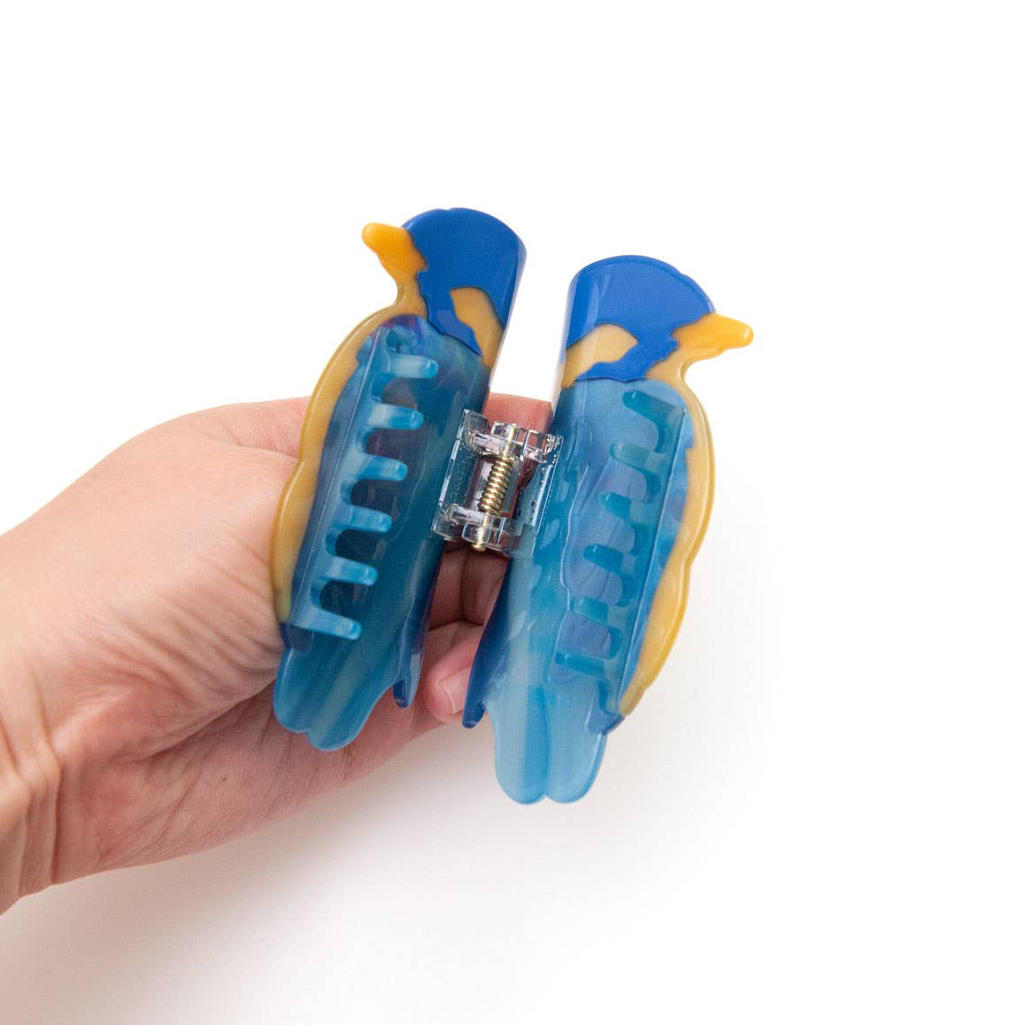 A hand holding a blue and yellow Blue Bird Hair Claw Clip shaped like a bird.