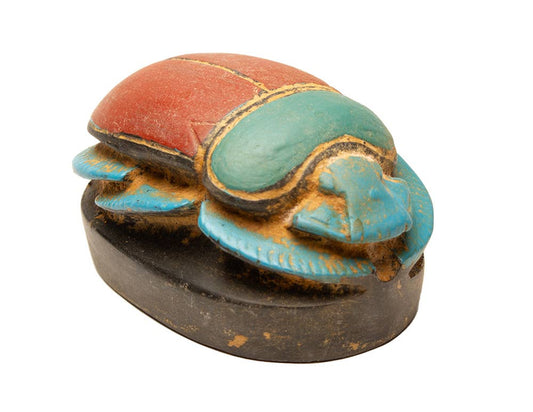 Presenting the “Egyptian Scarab Red - 1.5”,“ a handmade amulet inspired by ancient Egyptian art, expertly carved and painted with vibrant red, green, and blue colors atop a black base.