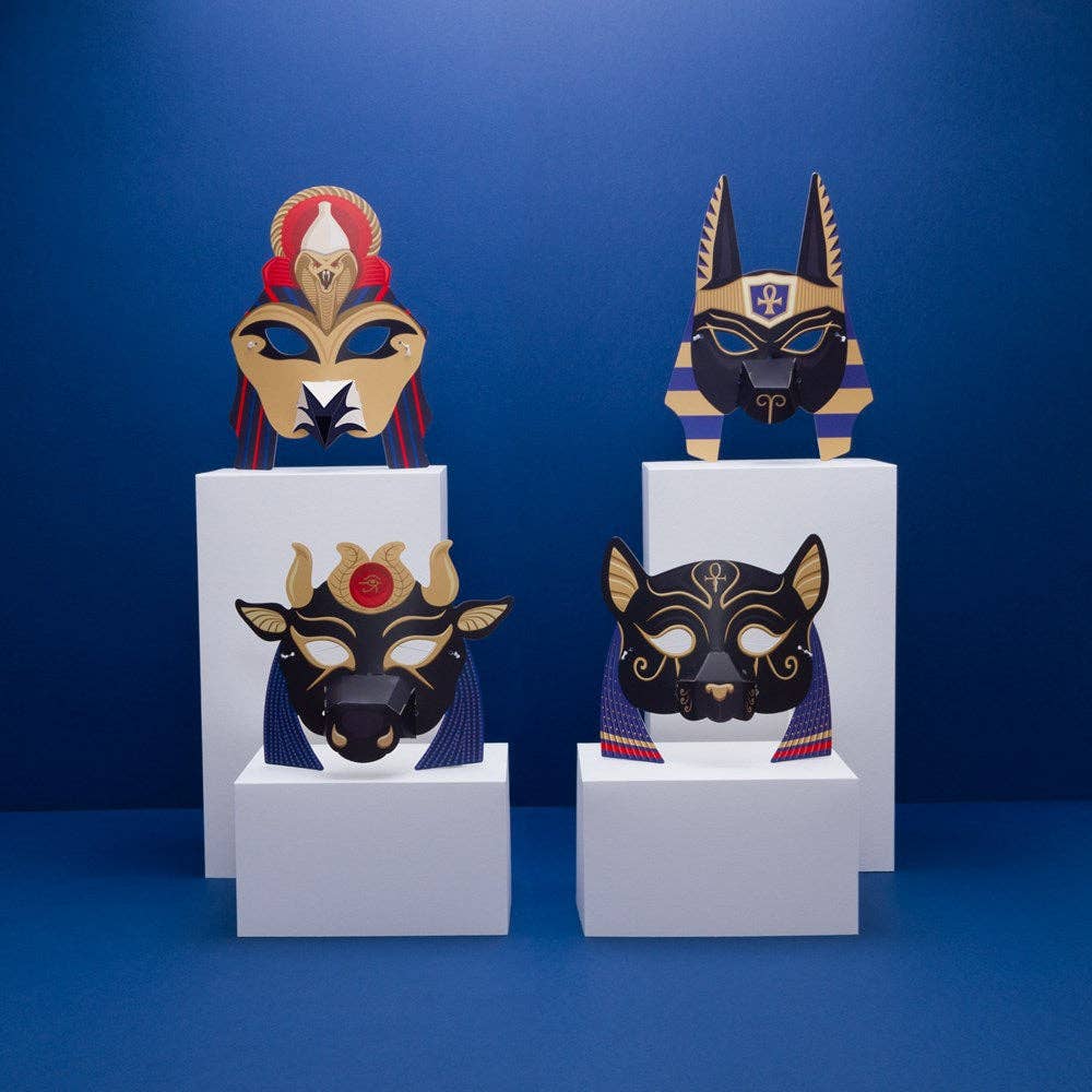 Create Your Own Egyptian Gods Animal Masks are displayed on white pedestals against a blue backdrop. Each mask features intricate patterns and gold, black, red, or blue accents—ideal for a fun ancient Egyptian activity.