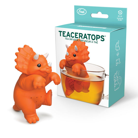 An orange TEACERATOPS Dinosaur Tea Infuser stands next to its retail box, which displays an illustration of the loose leaf infuser hanging inside a glass mug of tea.