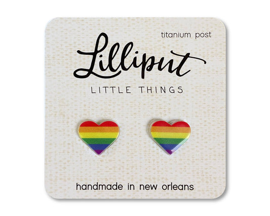Two heart-shaped rainbow earrings from the “Pride Earrings // LGBTQ+ Pride Flag Earrings” collection are displayed on a card labeled Lilliput Little Things; these handmade earrings are carefully crafted in New Orleans and feature hypoallergenic titanium posts.