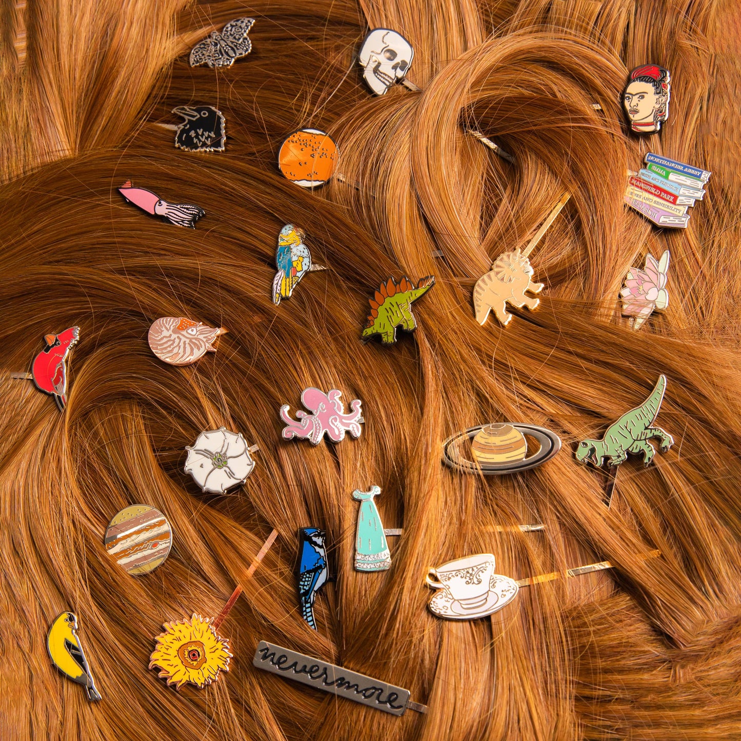 Songbird Hair Pins, featuring designs like Northern Cardinal, planets, books, and a Frida Kahlo portrait, are scattered artistically throughout wavy light brown hair for a vibrant display.