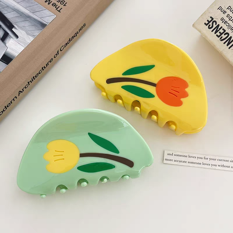 Two Tulip Hair Claw Clips: one yellow with an orange flower and one green with a yellow flower.