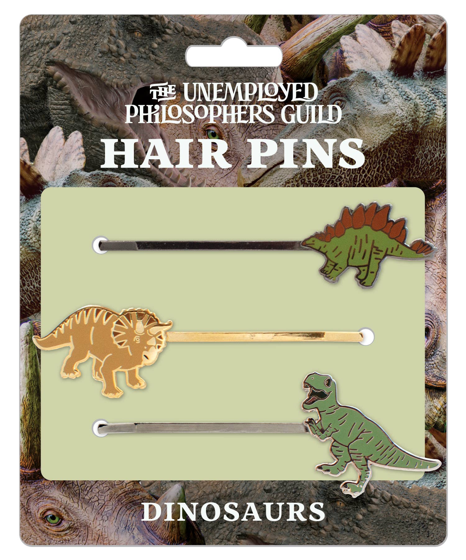 Dinosaur Hair Pins: Three pins featuring a Stegosaurus mohawk, Triceratops frill, and T. rex, all on a card with playful dinosaur faces. From The Unemployed Philosophers Guild.