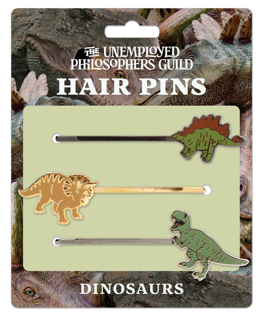 Dinosaur Hair Pins: Three pins featuring a Stegosaurus mohawk, Triceratops frill, and T. rex, all on a card with playful dinosaur faces. From The Unemployed Philosophers Guild.
